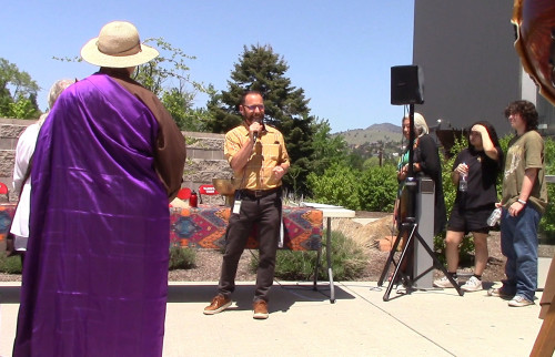 Tony Swan stands in fornt of a table and address the crowd outside